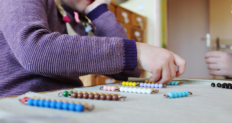 Ein Kind spielt mit Montessori-Perlenketten