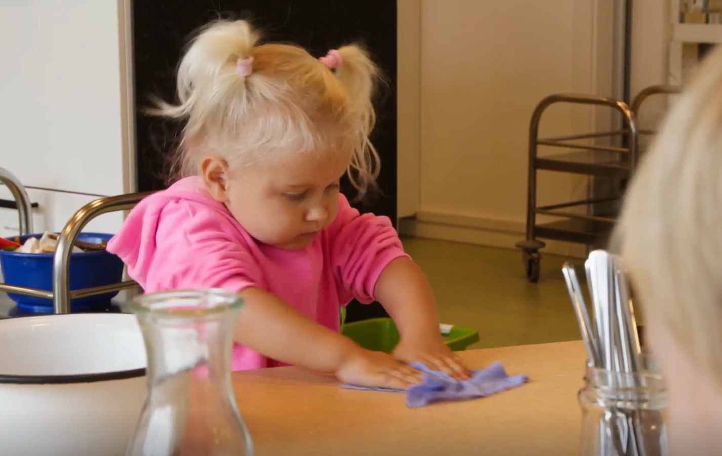 Ein kleines Kind putzt den Tisch mit einem Lappen